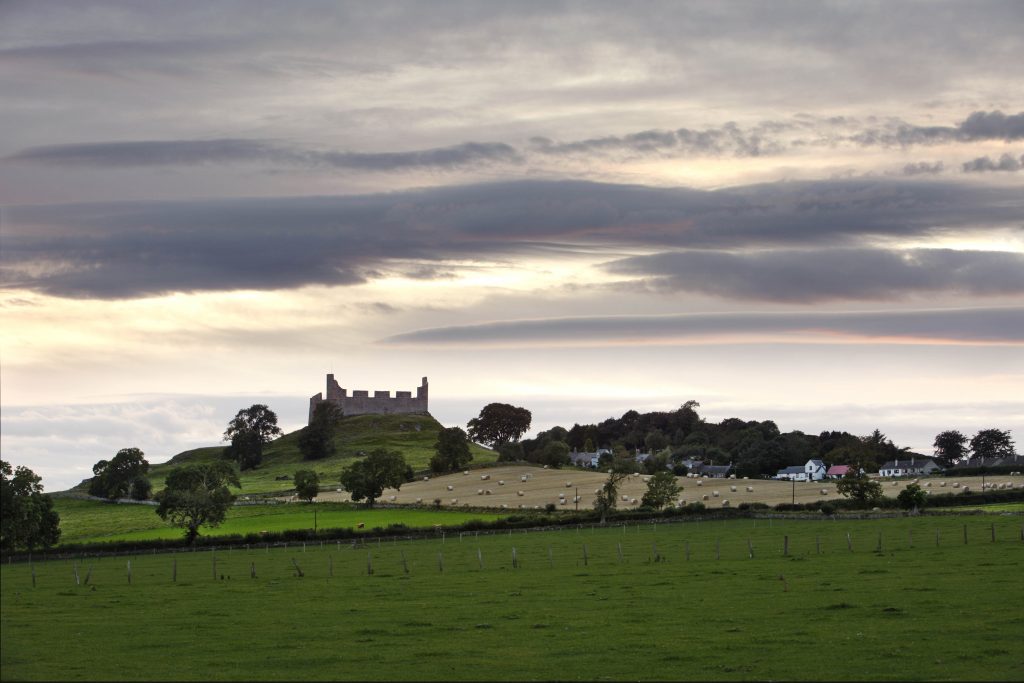 Hume castle viewed from a distance across some fields.